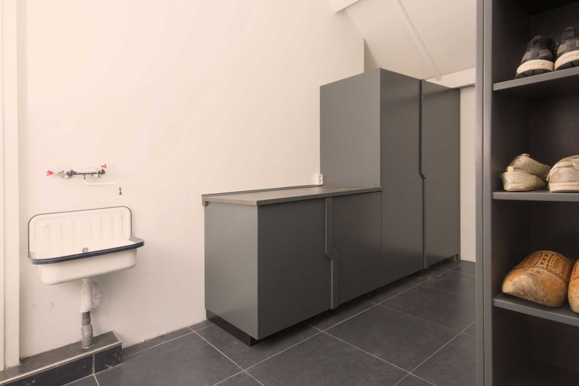 Op maat gemaakte bijkeuken met hoge bergkasten in grijs